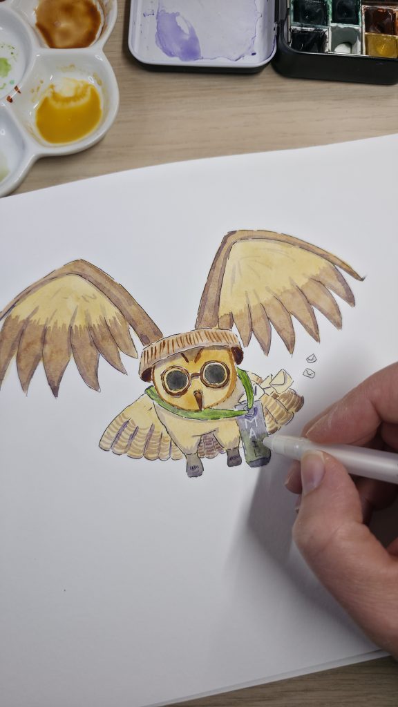 Photographie d'une main d'artiste utilisant un stylo blanc pour ajouter des détails sur une illustration à l'aquarelle représentant un petit hibou facteur avec des lunettes et une sacoche de courrier.